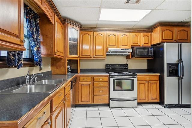 kitchen featuring a drop ceiling, appliances with stainless steel finishes, sink, and light tile patterned flooring