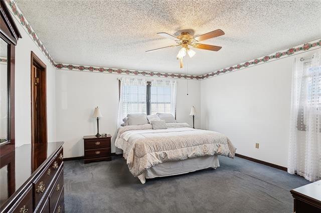 bedroom with a textured ceiling, ceiling fan, and dark carpet