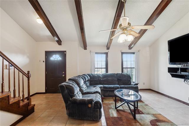 tiled living room featuring vaulted ceiling with beams and ceiling fan