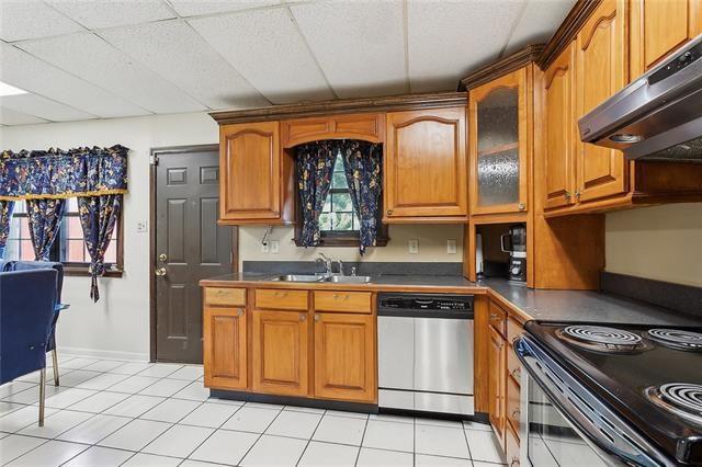 kitchen featuring black range with electric cooktop, extractor fan, light tile patterned floors, sink, and dishwasher