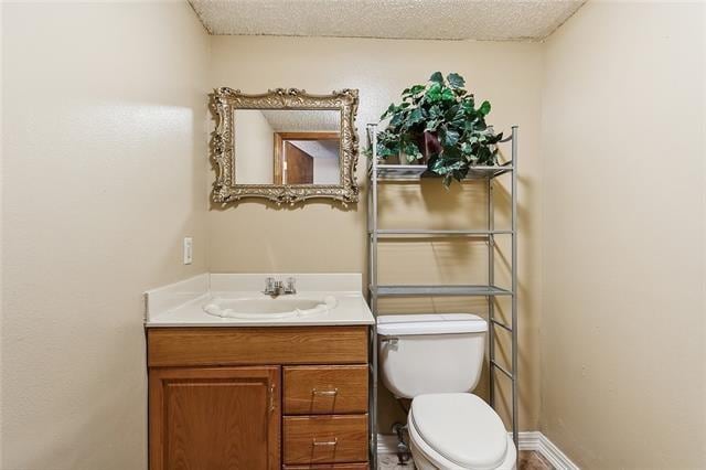 bathroom with toilet, vanity, and a textured ceiling