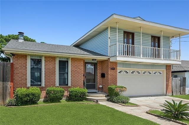 view of front of house with a garage, a front lawn, and a balcony