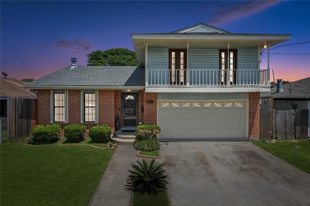 view of front of property with a garage, a yard, and a balcony