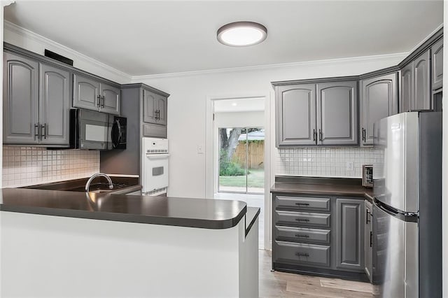 kitchen featuring white oven, sink, light hardwood / wood-style flooring, tasteful backsplash, and stainless steel refrigerator