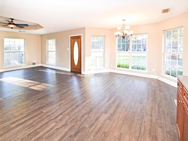 unfurnished living room featuring dark hardwood / wood-style flooring, a healthy amount of sunlight, and ceiling fan with notable chandelier