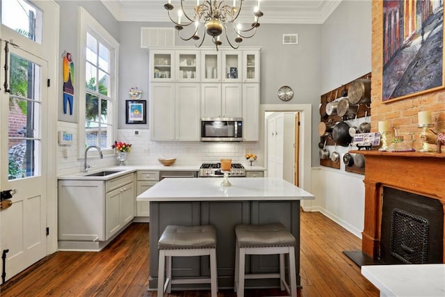 kitchen featuring dark wood-type flooring, a kitchen island, appliances with stainless steel finishes, and sink