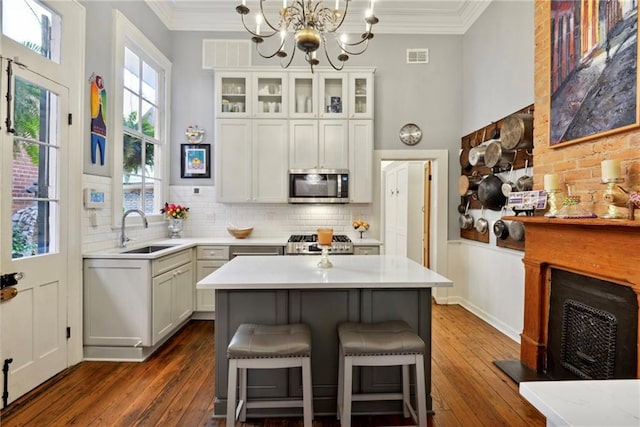 820B Saint Ann St, New Orleans, LA 70116 - kitchen featuring stainless steel microwave, a sink, dark wood finished floors, light countertops, and ornamental molding