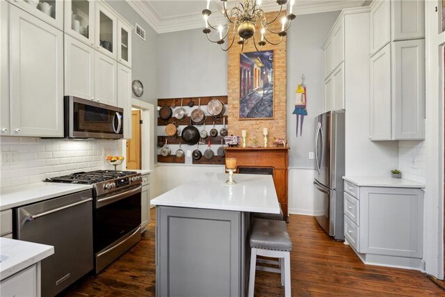 820B Saint Ann St, New Orleans, LA 70116 - kitchen featuring stainless steel appliances, ornamental molding, backsplash, light countertops, and glass insert cabinets