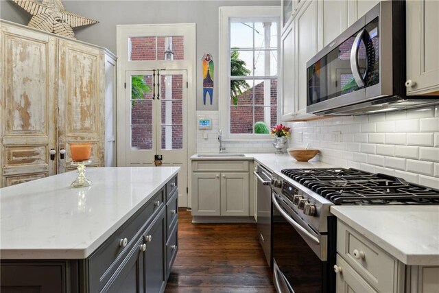 820B Saint Ann St, New Orleans, LA 70116 - kitchen with stainless steel appliances, a sink, dark wood-type flooring, tasteful backsplash, and a center island