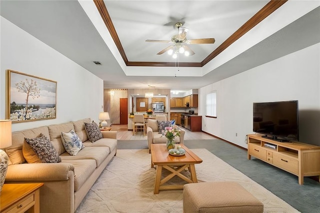 living room with carpet floors, a raised ceiling, ceiling fan, and ornamental molding