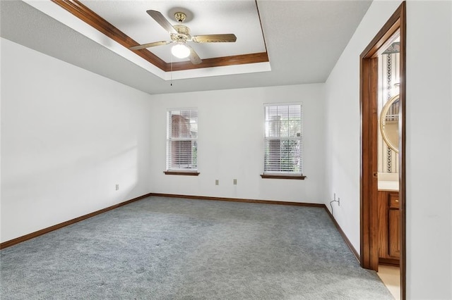 carpeted spare room with a tray ceiling and ceiling fan