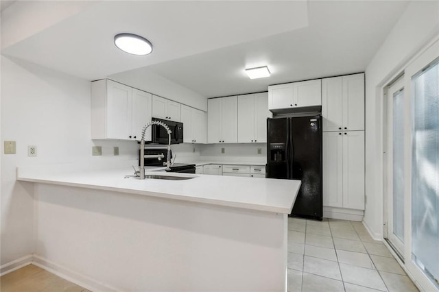 kitchen with kitchen peninsula, white cabinets, light tile patterned flooring, and black appliances