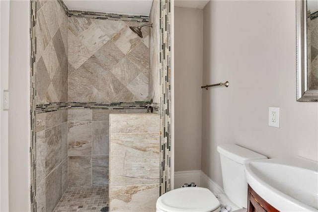 full bath featuring toilet, tiled shower, and vanity