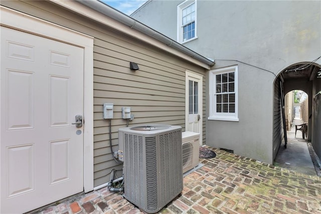 details featuring cooling unit, arched walkways, and stucco siding
