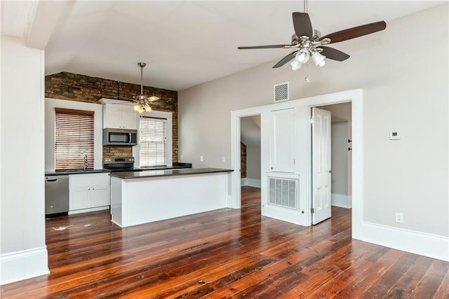 kitchen featuring a ceiling fan, visible vents, dark countertops, stainless steel appliances, and dark wood-style floors