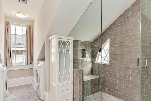 bathroom with a shower with door, washer / dryer, and vaulted ceiling