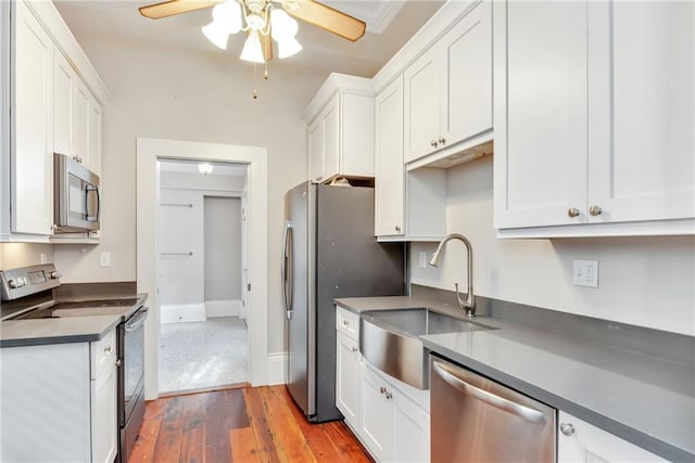 kitchen with appliances with stainless steel finishes, a sink, a ceiling fan, and white cabinets