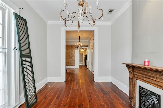 hallway featuring dark wood-type flooring, brick wall, an inviting chandelier, and crown molding