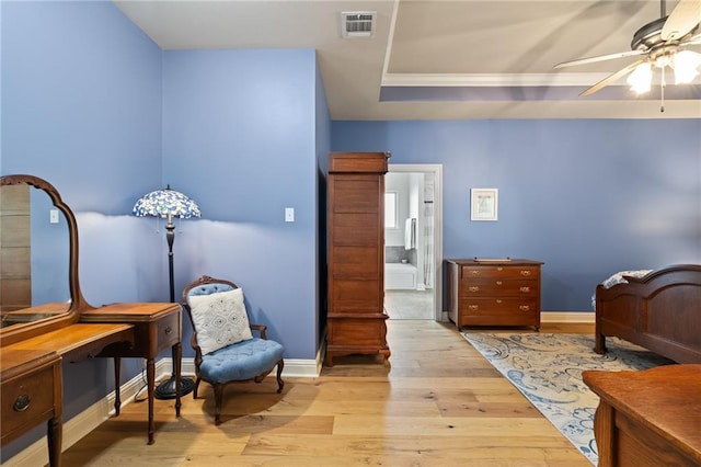 bedroom with light wood-type flooring, ceiling fan, and a tray ceiling