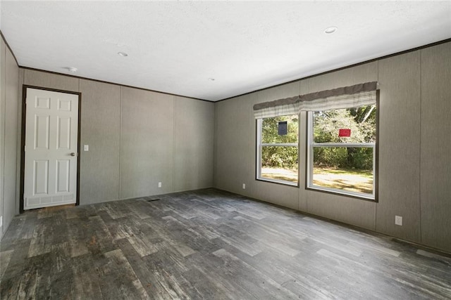 spare room featuring dark wood-type flooring and wood walls