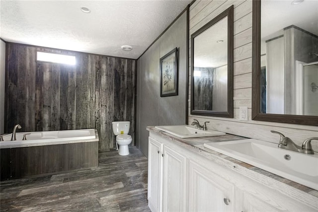 full bathroom with vanity, a textured ceiling, wood walls, hardwood / wood-style floors, and toilet