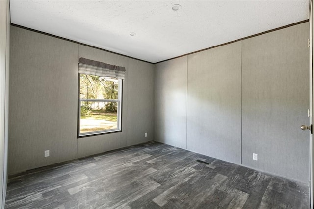 spare room featuring ornamental molding, a textured ceiling, and dark hardwood / wood-style floors