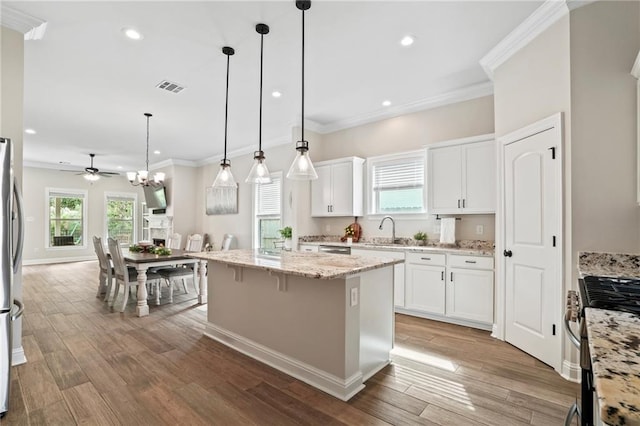 kitchen with white cabinets, hanging light fixtures, appliances with stainless steel finishes, and a center island