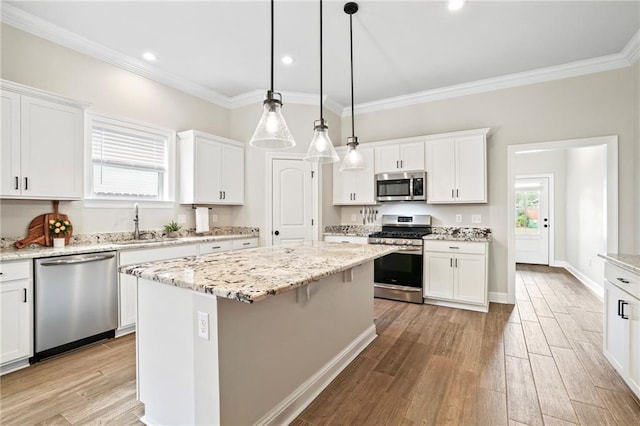 kitchen with white cabinets, a kitchen island, appliances with stainless steel finishes, and light hardwood / wood-style flooring