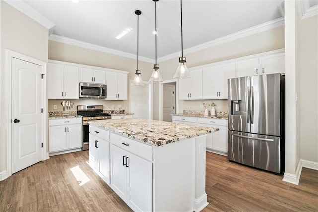 kitchen featuring stainless steel appliances, white cabinets, pendant lighting, and a center island