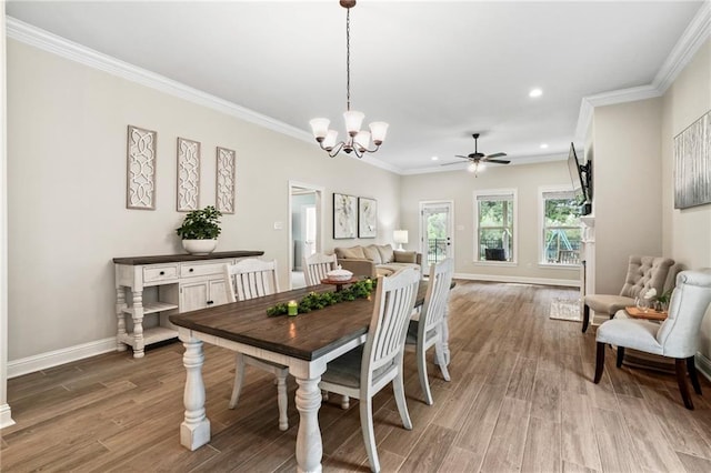 dining room with wood-type flooring, ceiling fan with notable chandelier, and crown molding