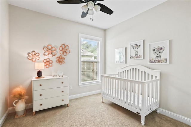 carpeted bedroom with ceiling fan and a nursery area