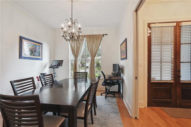 dining space featuring an inviting chandelier, light hardwood / wood-style flooring, and ornamental molding