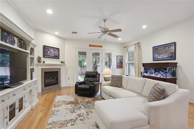 living room with ornamental molding, ceiling fan, and light hardwood / wood-style flooring