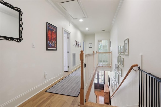 hall with wood-type flooring, a healthy amount of sunlight, and crown molding