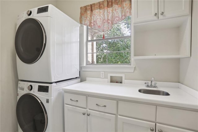 clothes washing area featuring cabinets, sink, stacked washer and dryer, and plenty of natural light