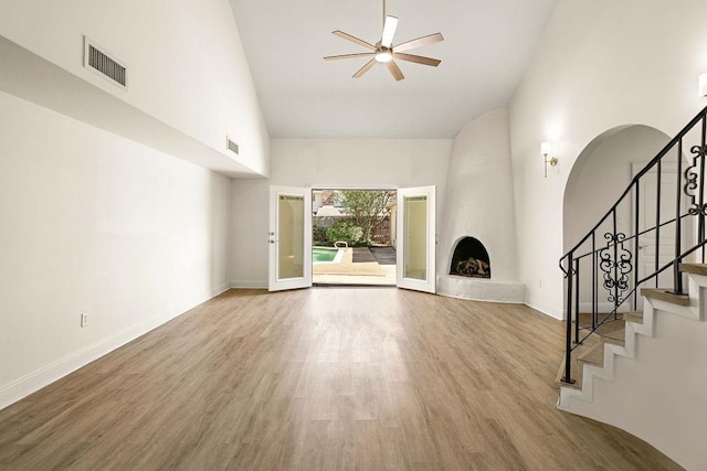 unfurnished living room featuring a large fireplace, high vaulted ceiling, light hardwood / wood-style floors, and ceiling fan