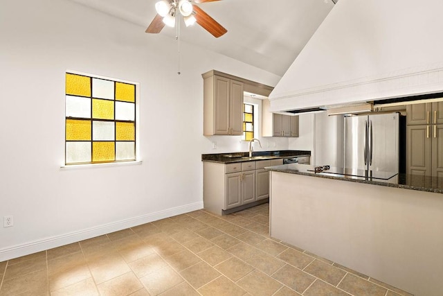 kitchen with dark stone counters, stainless steel refrigerator, sink, lofted ceiling, and ceiling fan