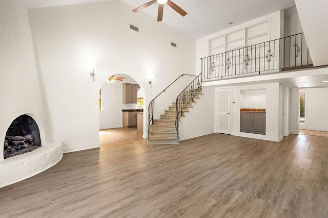 unfurnished living room featuring high vaulted ceiling, hardwood / wood-style flooring, and ceiling fan