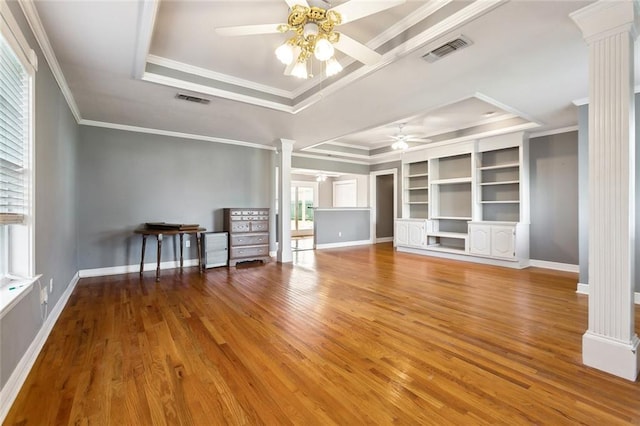 unfurnished living room with ornate columns, hardwood / wood-style flooring, ceiling fan, and a tray ceiling