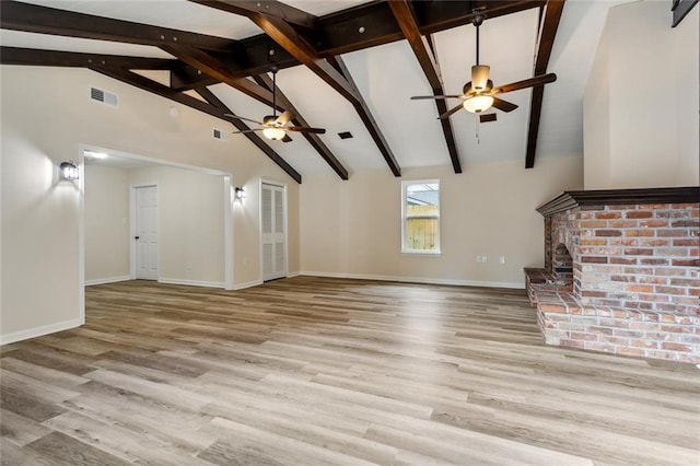 unfurnished living room with light hardwood / wood-style floors, high vaulted ceiling, beamed ceiling, ceiling fan, and a fireplace