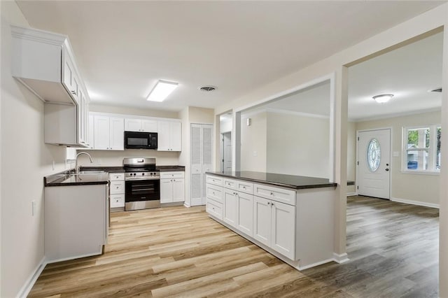 kitchen with sink, light wood-type flooring, stainless steel range oven, and white cabinets