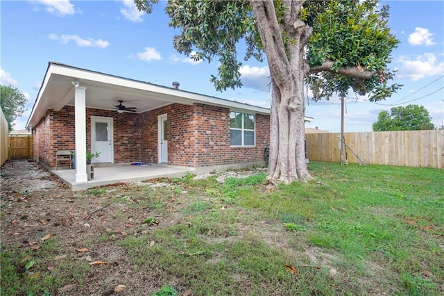 back of property with ceiling fan, a yard, and a patio