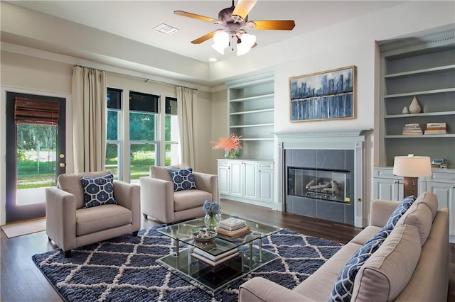 living room featuring a fireplace, built in features, dark hardwood / wood-style floors, and ceiling fan