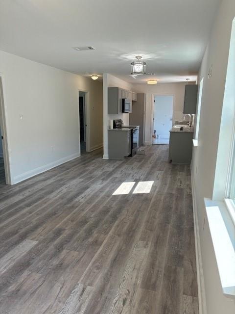 unfurnished living room featuring dark wood-type flooring and sink