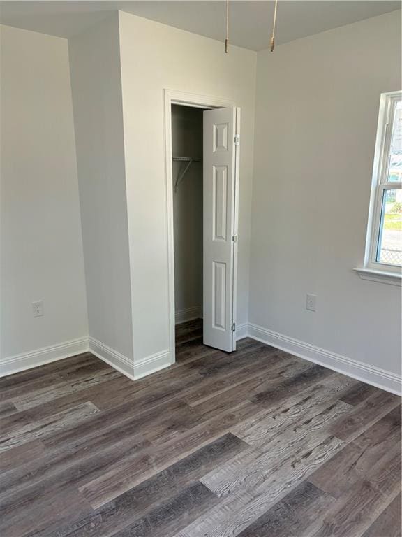 unfurnished bedroom with dark wood-type flooring and a closet