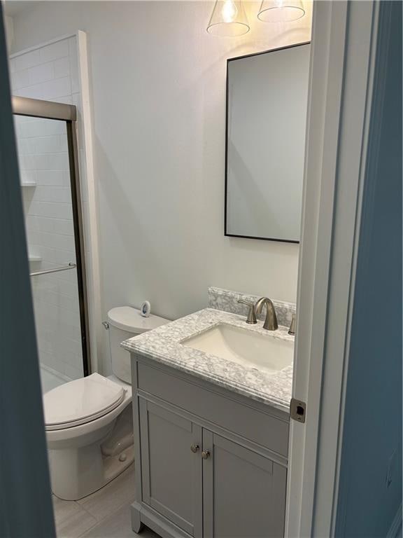 bathroom featuring walk in shower, tile patterned flooring, vanity, and toilet