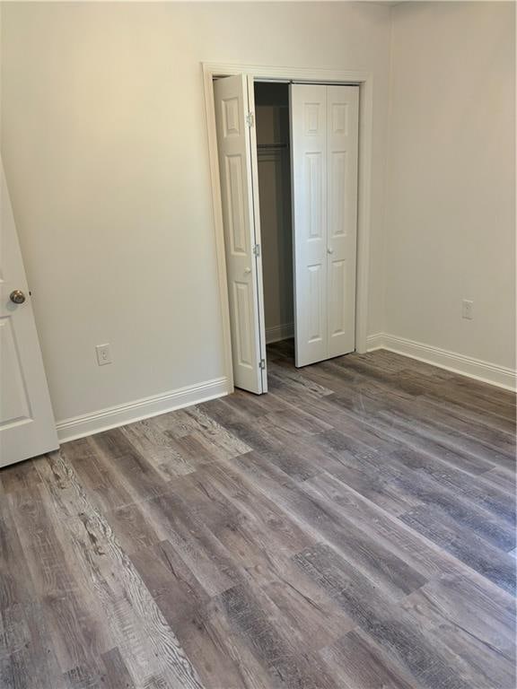 unfurnished bedroom featuring dark wood-type flooring and a closet