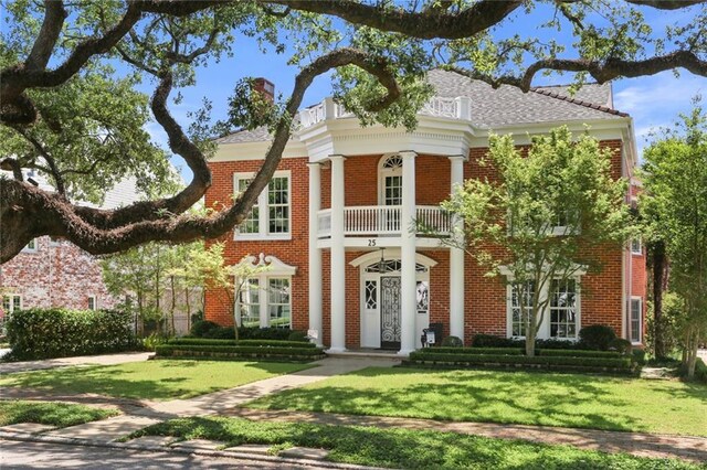 greek revival house with a balcony and a front yard