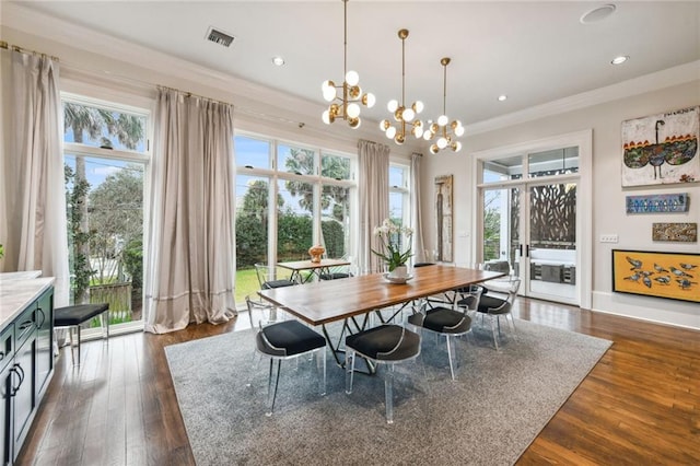 dining room with dark hardwood / wood-style flooring, ornamental molding, and a notable chandelier