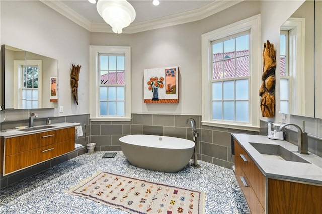 bathroom with a wealth of natural light, vanity, tile walls, and crown molding